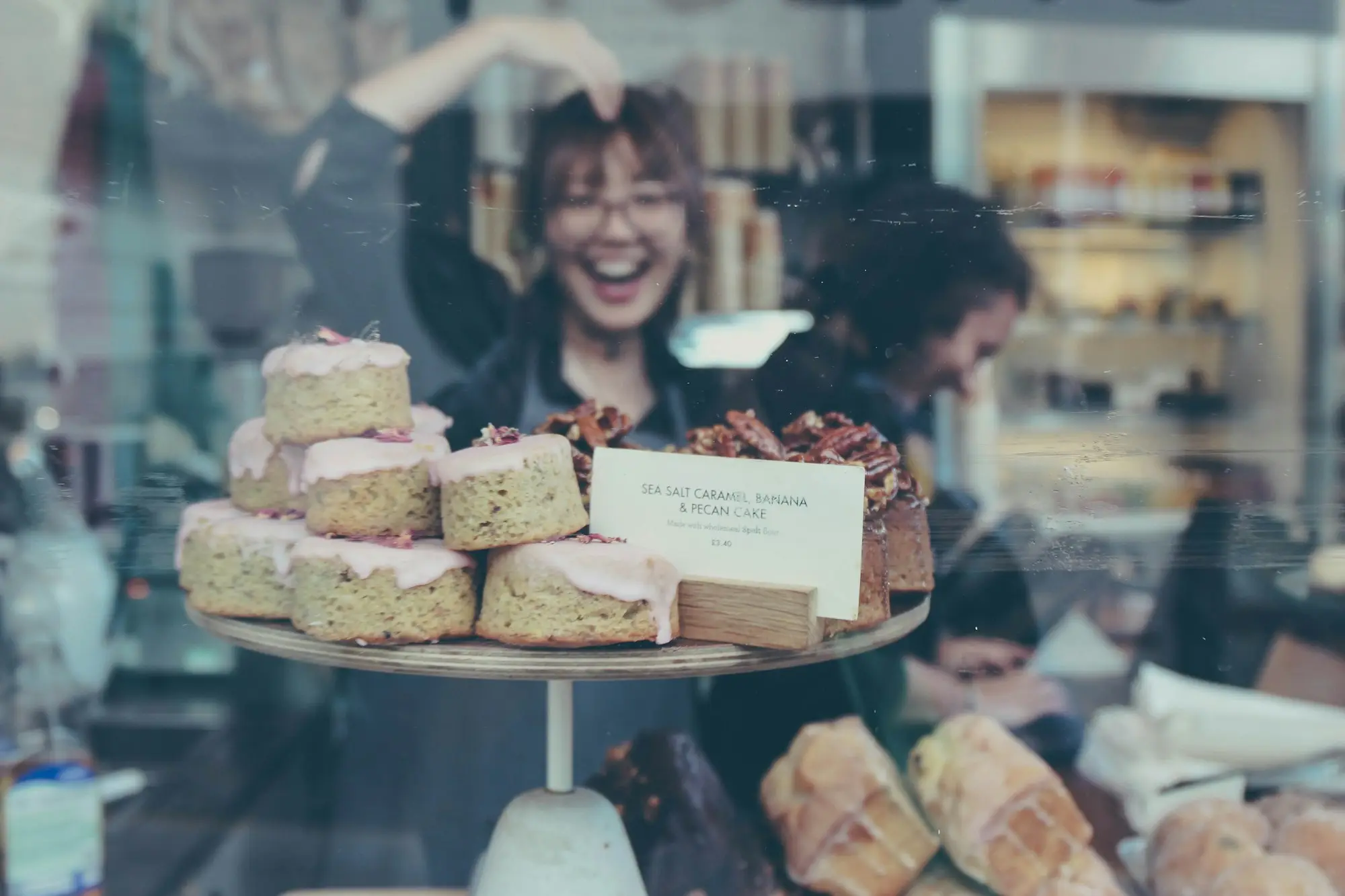 Smiling bakery owner reflected in a food display case, a business that draws on a line of credit