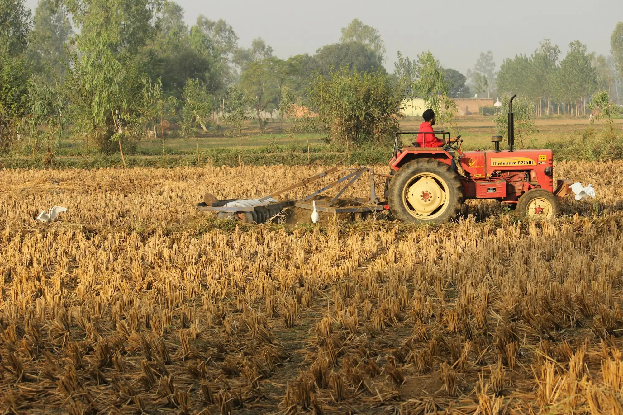 Red tractor working a brown paddock, a long-lived asset matched to a longer loan term